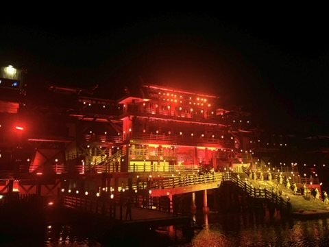 Beleuchtete Holzarchitektur am Wasser bei Nacht